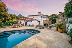 A view of a beautiful backyard with an inground pool and outdoor dining table